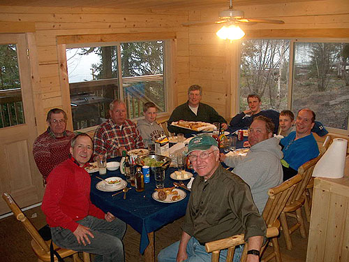 This is a photo of a group of fisherman and their kids sitting down to a big dinner