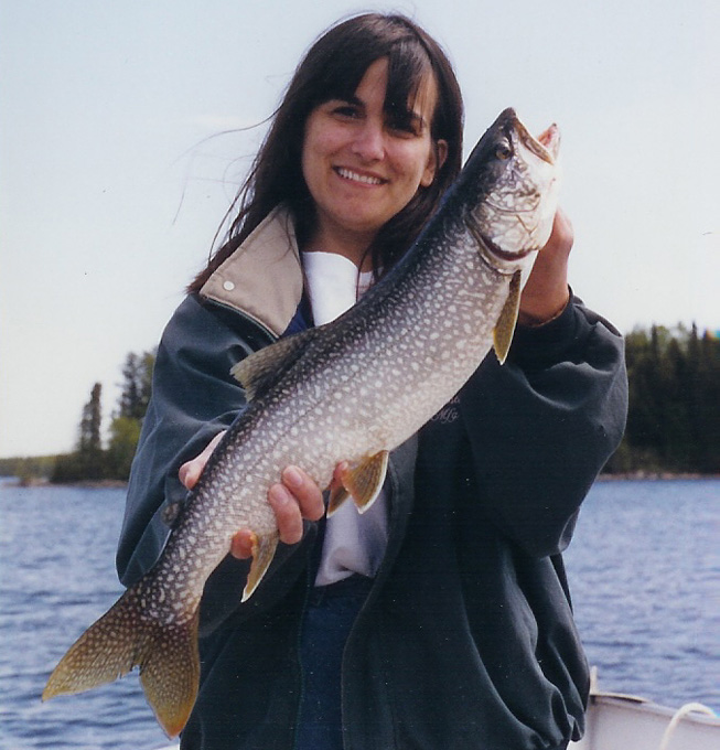 This is a woman in a dark blue jacket holding up a 5 pound Lake Trout