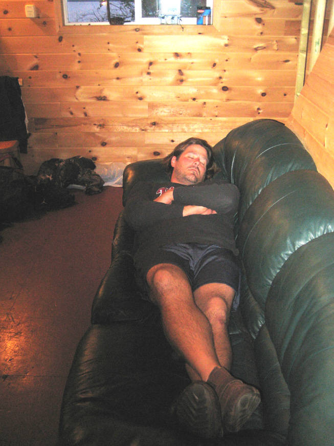 This is a photo of a man sleeping on a leather couch