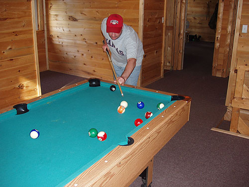 This is a photo of a man shooting pool inside one of the big cottages