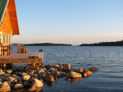 This is a photo of a the waterfront porch on the side of a cottage with a beautiful view of the lake