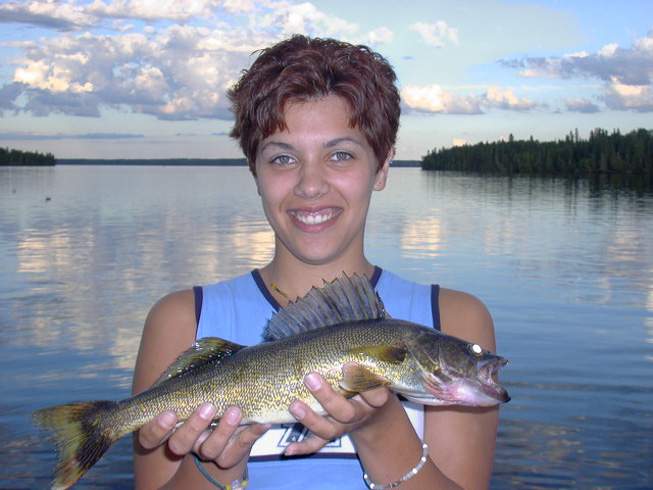 This is a photo of a young lady holding a small Walleye