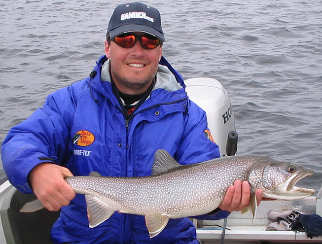 This is a picture of a man in a blue jacket holding a 8 pound Lake Trout