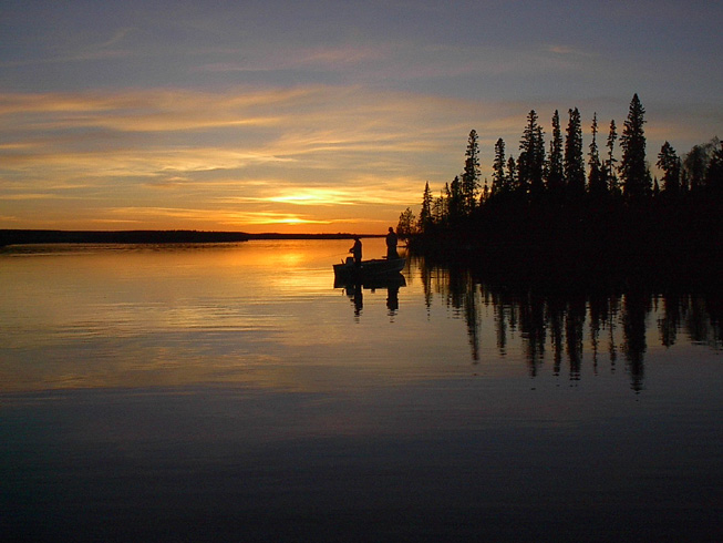 This is a photo of a fishing boat out on the lake in the evening after the sun has set.