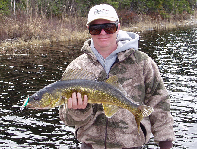 This is a picture of a man in a brown jacket holding up a 4.5 pound Walleye